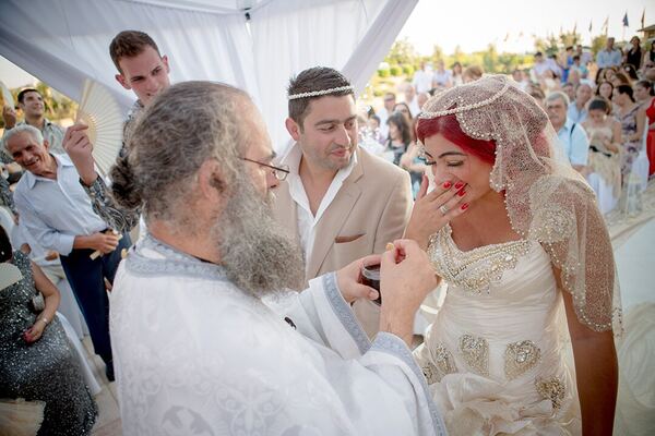 The priest blessing the couple at an outdoor wedding ceremony at The Elysium, Paphos, photographed by Evagoras Mandrides
