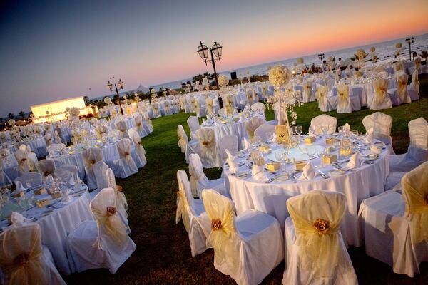 Wedding reception tables on the lawn at dusk at The Elysium, Paphos, photographed by Evagoras Mandrides