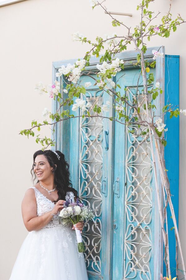 A bride by a blue door on her wedding day in Cyprus, photographed by Evagoras Mandrides