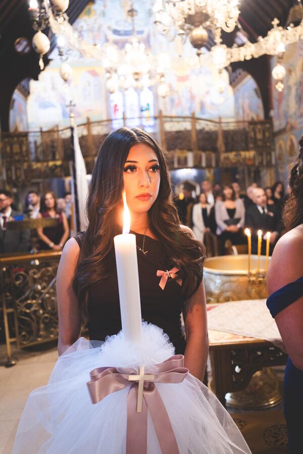 The godmother holding the christening candle at the Twelve Apostles, Brookmans Park, photographed by Evagoras Mandrides
