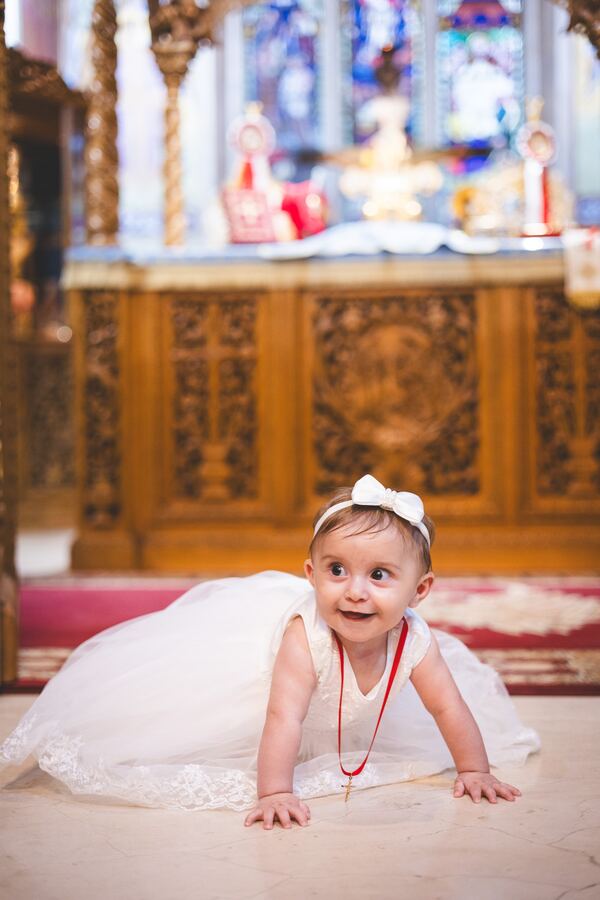 A baby in front of the iconostasis at a christening in Brookmans Park, photographed by Evagoras Mandrides